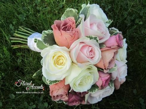 Handtied bridal bouquet of soft pink Sweet Avalanche roses, ivory cream Avalanche roses, dusky pink Dark Hypnose roses, and Cafe Latte garden roses with variegated pittosporum