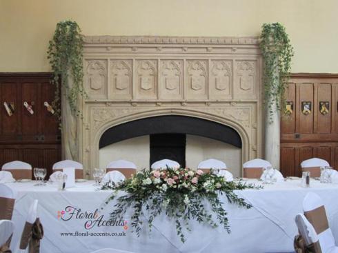 Traditional long and low top table arrangement of pale pinks, creams and dusky pinks